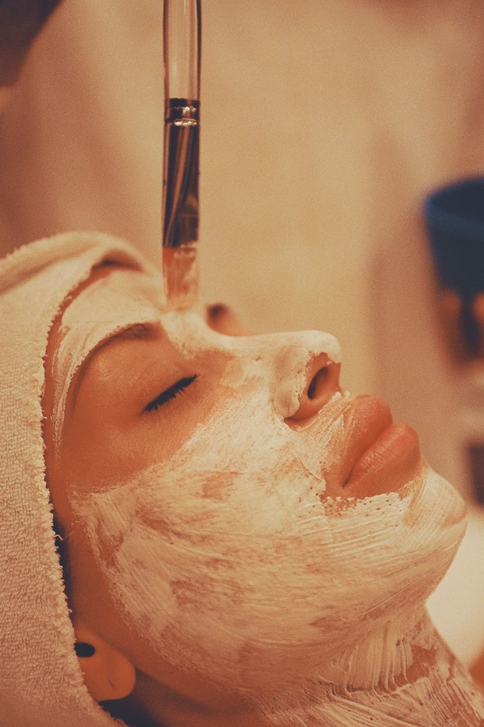 Services Adult woman receiving a soothing facial mask application at a modern spa.